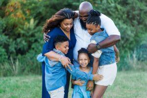 Family embracing each other in an area full of greenery. Life insurance is what made it happen.